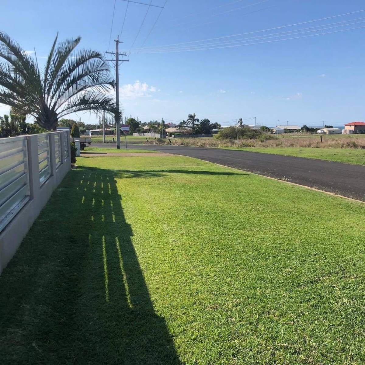 A wide mown verge lawn running along a fence line