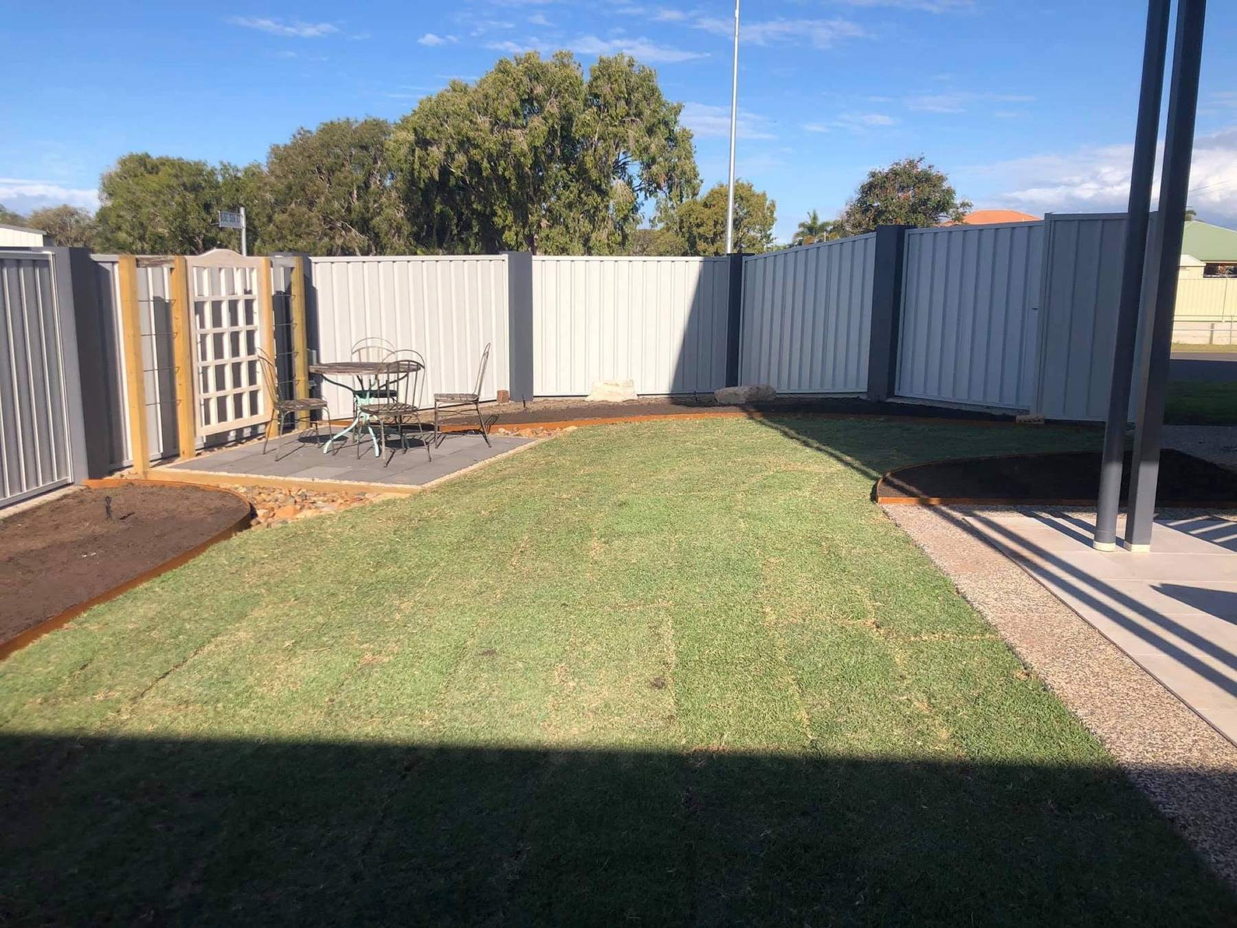 A turfed backyard with a patio and a colorbond fence