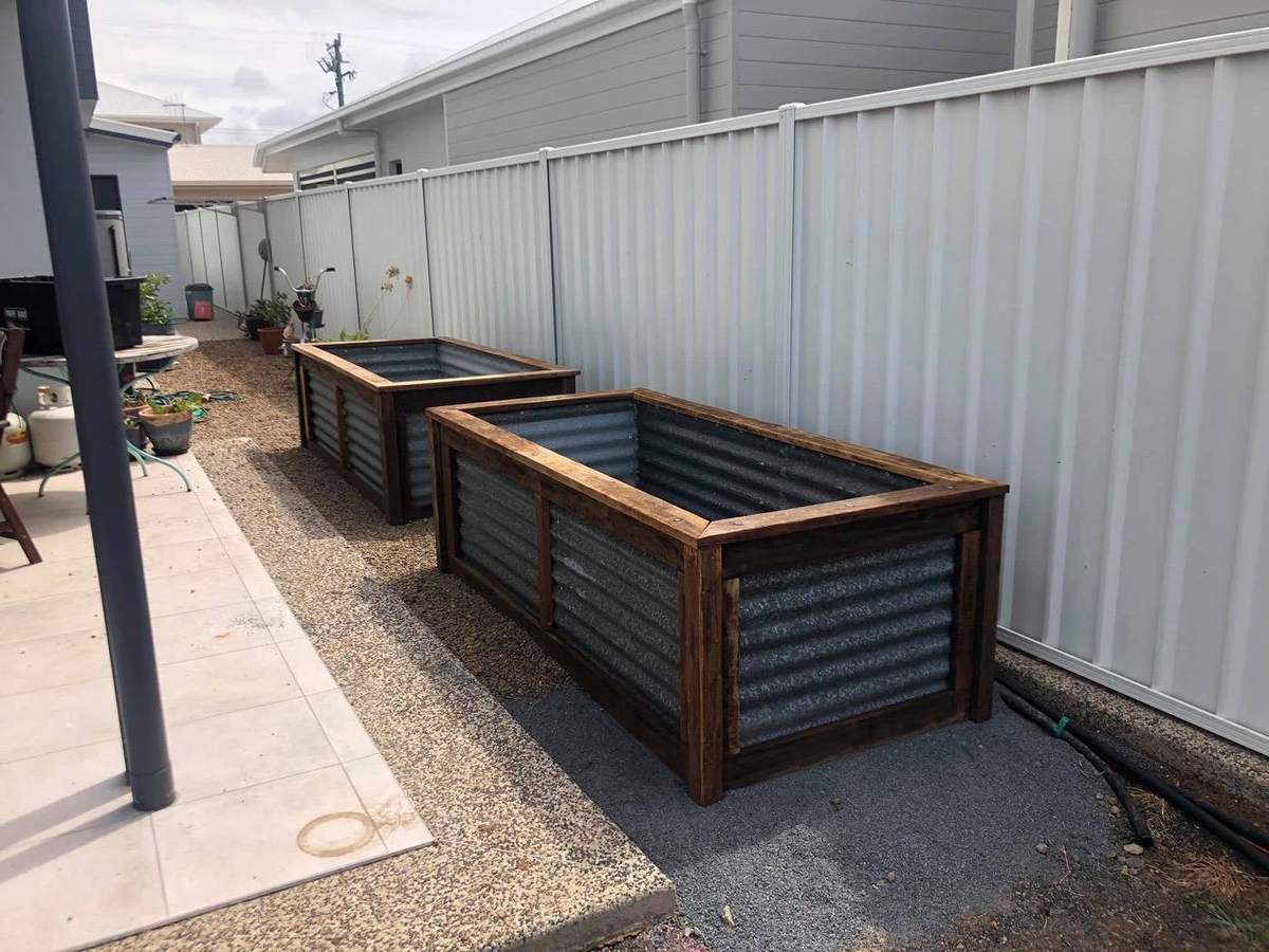 Two corrugated planter boxes with timber frames built beside a path