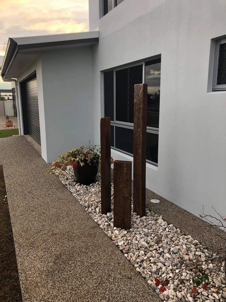 Three upright timber posts standing in a bed of white pebbles