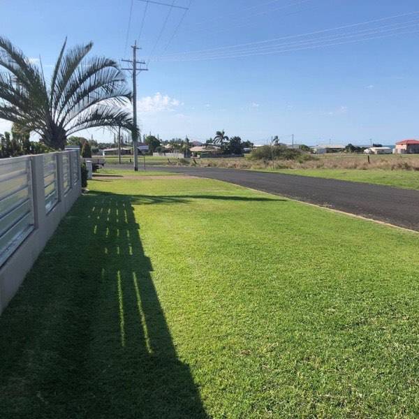 A wide mown verge lawn running along a fence line