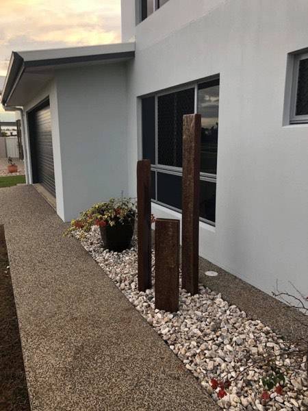 Three upright timber posts standing in a bed of white pebbles