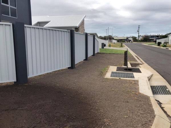 A concrete path running between a colorbond fence and a house