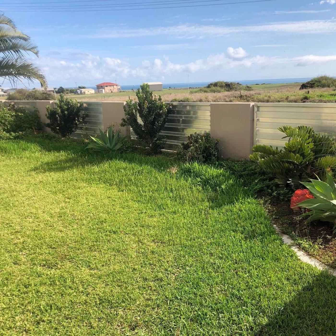 A mown lawn behind a low fence with the sea beyond